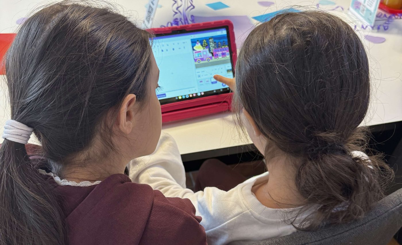 Två barn programmerar tillsammans i ScratchJr på surfplatta
